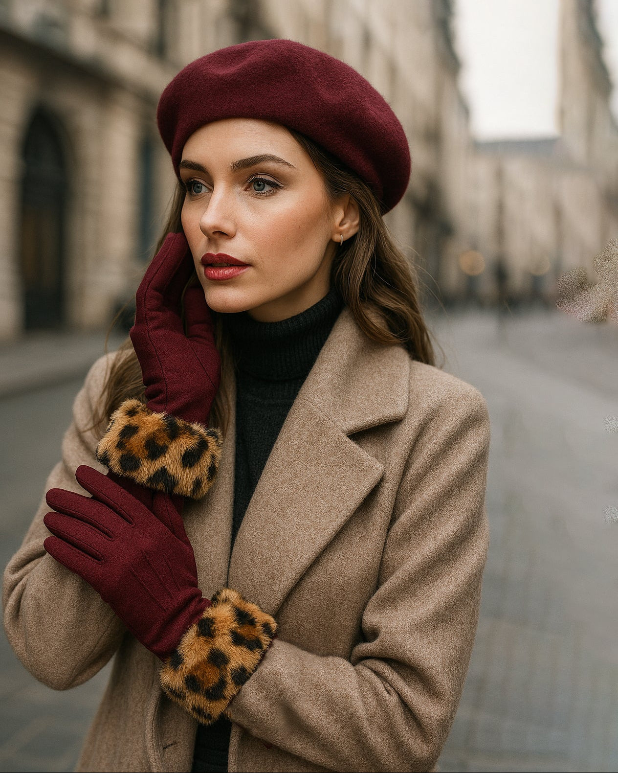 Woman wearing a burgundy beret, coat, and gloves with leopard print cuffs on a city street.